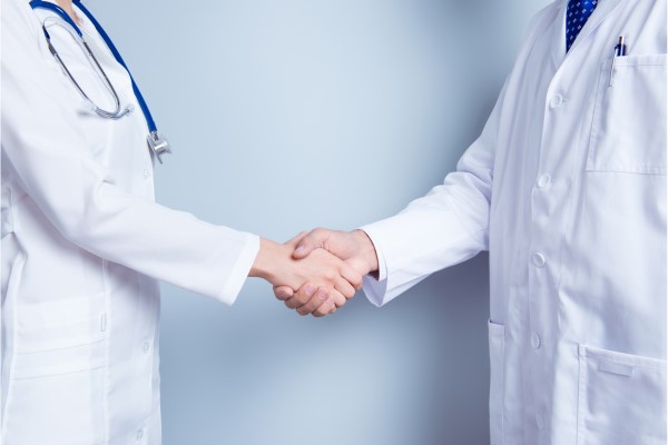 A dentist and medical doctor shaking hands.